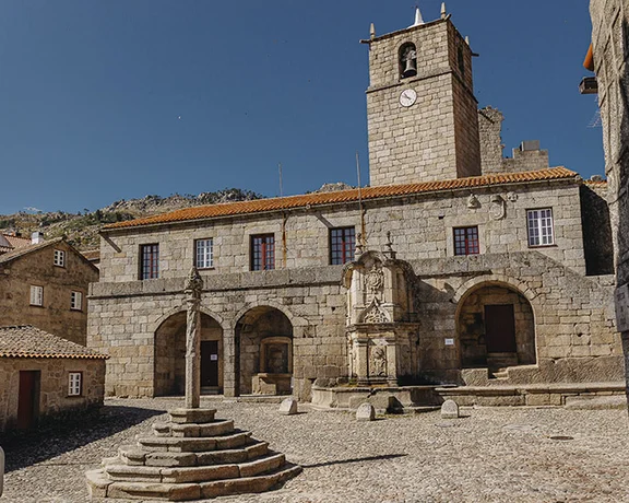 Stone village square with historic town hall and clock tower in Castelo Novo, Portugal