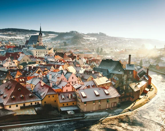 Snow-dusted rooftops of Český Krumlov at sunrise by the Vltava River.