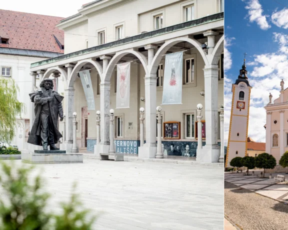 Town square with a statue and columns on the left, white church with towers on the right.
