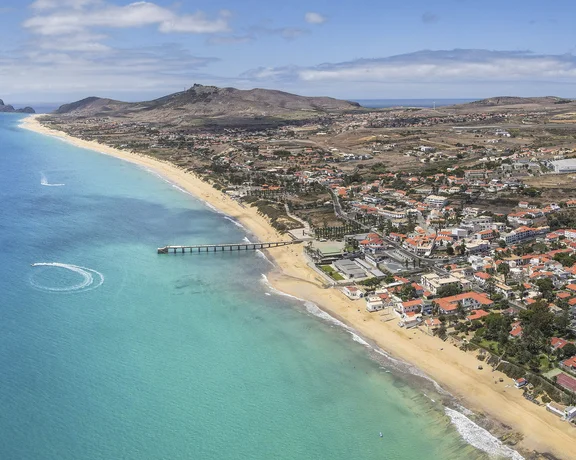 Aerial view of a coastal town with turquoise water and a sandy beach.