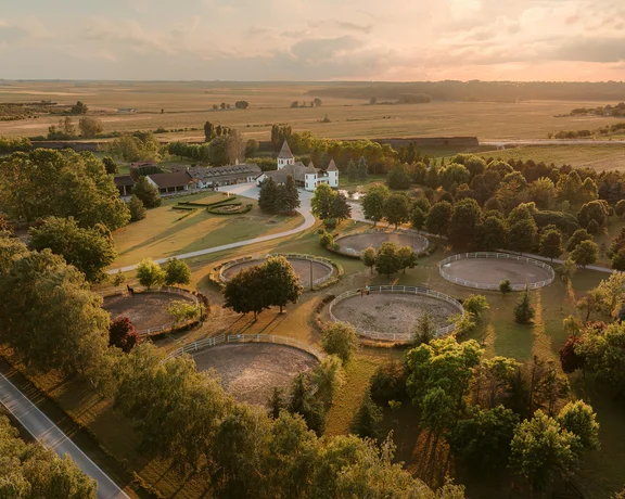 Aerial view of a rural wastewater treatment plant surrounded by trees at sunset.