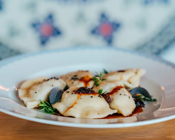 Dumplings topped with herbs and sauce on a white plate.