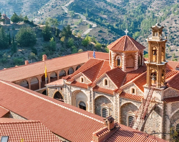 Stone monastery with red-tiled roofs set in a mountainous landscape.