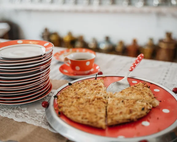 Sliced pie on a red polka dot plate next to stacked plates and a teacup.