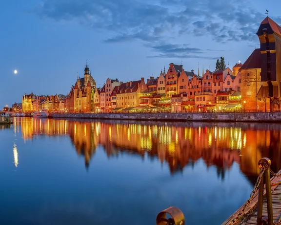 Colorful riverside buildings reflecting on calm water at dusk.