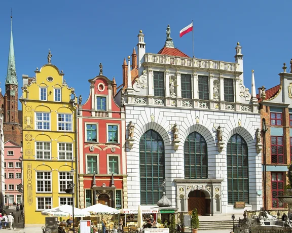 Colorful historic buildings and a white building with arched windows under a blue sky.