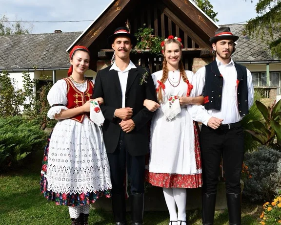 Two women and two men in traditional Hungarian folk costumes standing outdoors.