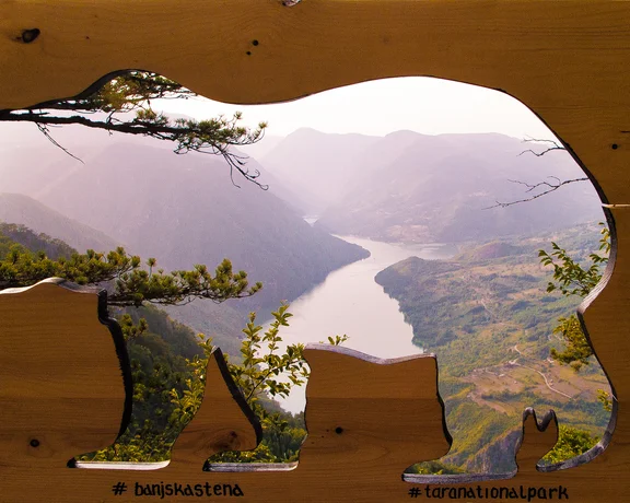 Mountain valley and river seen through a bear-shaped wooden cutout.