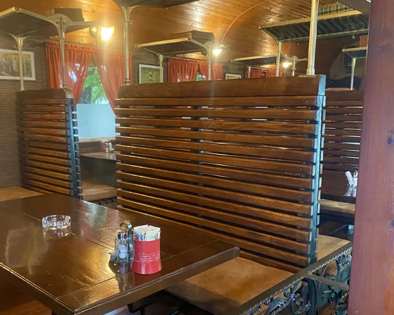 Wooden booths in a cozy restaurant with warm lighting and red curtains.