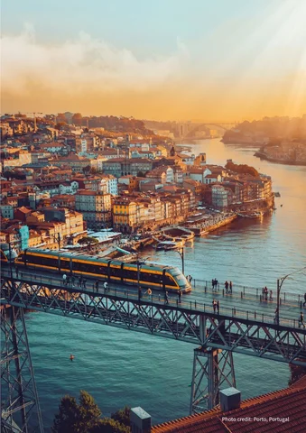 Train crossing Dom Luís I Bridge over Douro River in Porto at sunset.