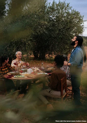 Four people enjoying an outdoor meal together at a rustic table in a garden.