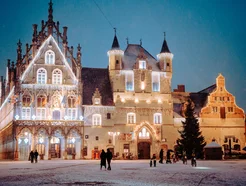 Centro histórico de Malinas, Bélgica, cubierto de nieve: edificios medievales, calles empedradas y una torre de iglesia bajo un cielo invernal.