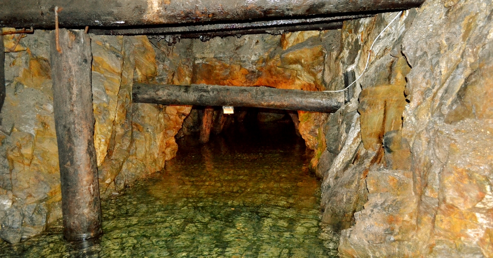 Subterranean passage in the Riese complex surrounded by rocks and water.
