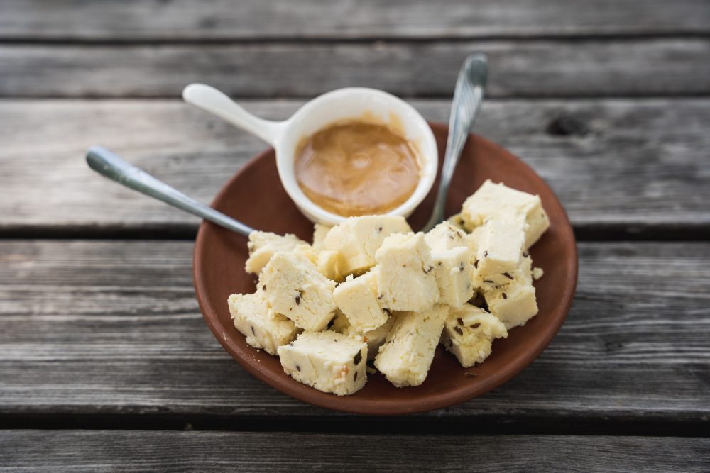Plate of Estonian farmhouse cheese cubes with caraway seeds, served with a small dish of jam or sauce at Taarka Taro KöögiKono restaurant.