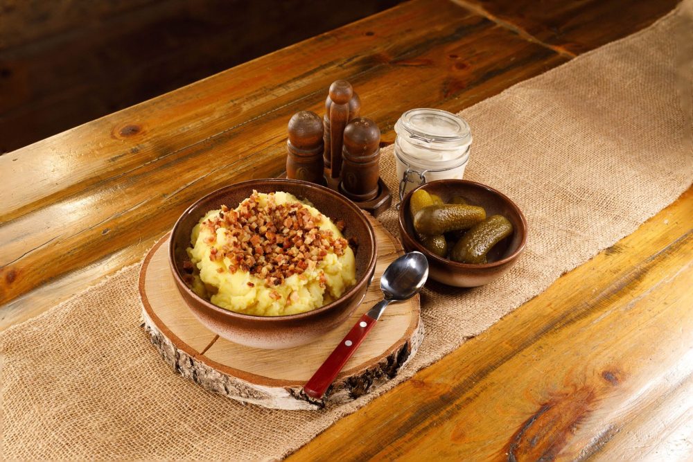 Traditional Estonian dish of mashed potatoes with fried bacon bits, served with pickles and sour cream at Kolu Tavern in the Estonian Open-Air Museum.