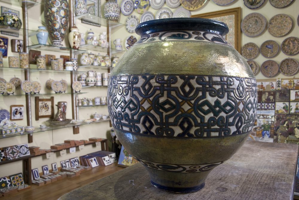 A beautifully designed decorative pot with intricate patterns, displayed in a shop surrounded by various ceramic artworks.