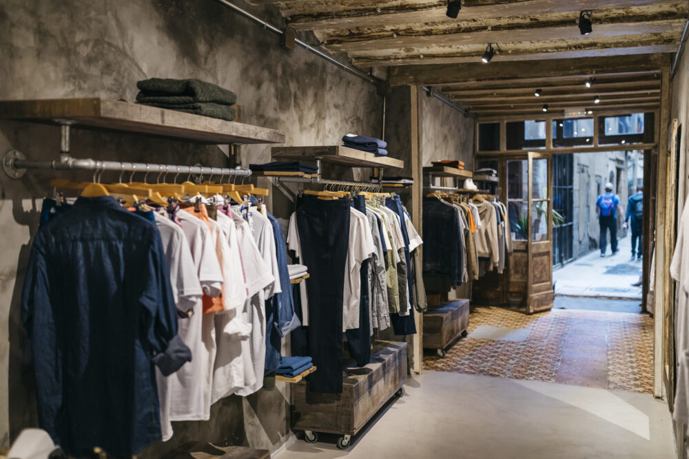 A boutique showcasing arranged racks of clothing in a rustic interior.