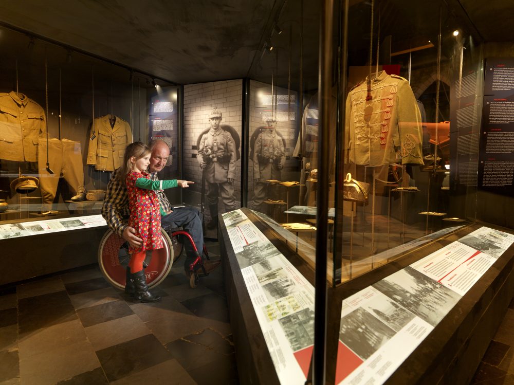 “Inside the museum, a girl pointing at the soldier section while accompanied by an adult in a wheelchair.