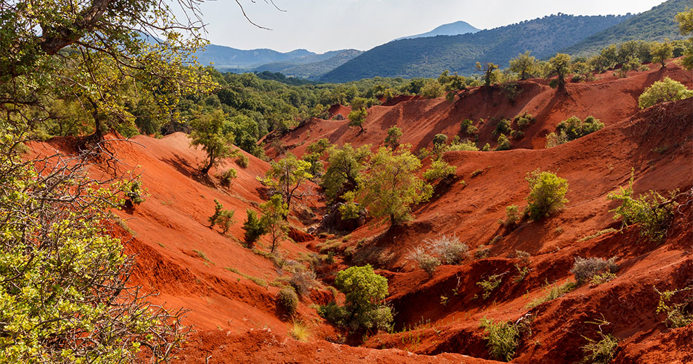 Travel through red clay terrain, a rare geological phenomenon in the Epirus region.