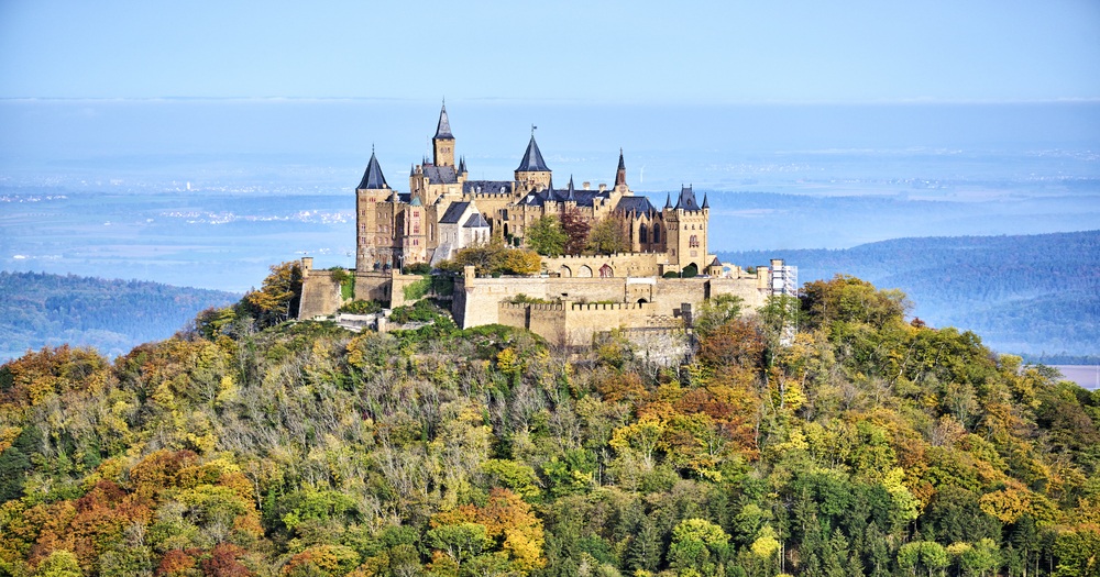 Hohenzollern Castle perched on a hill surrounded by colorful autumn foliage in Hechingen, Germany.