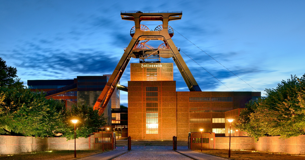 Heritage-listed Zollverein Colliery in Essen, Germany, illuminated at night with architectural lighting highlighting its industrial structures.