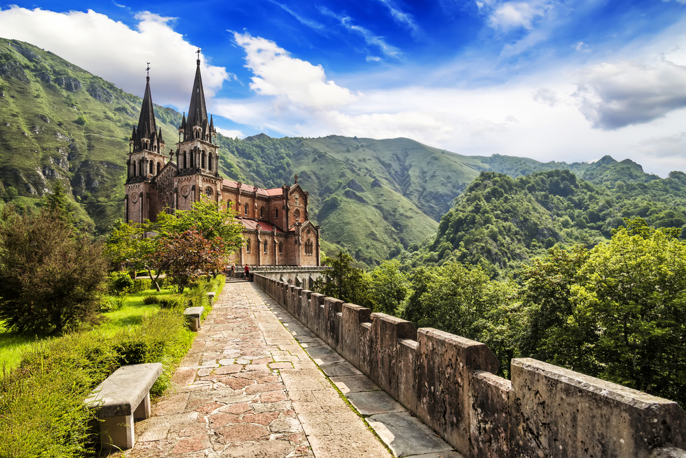 Visit Picos de Europa National Park, where the Basilica of Santa María la Real de Covadonga rises like a dream in the middle of a valley.