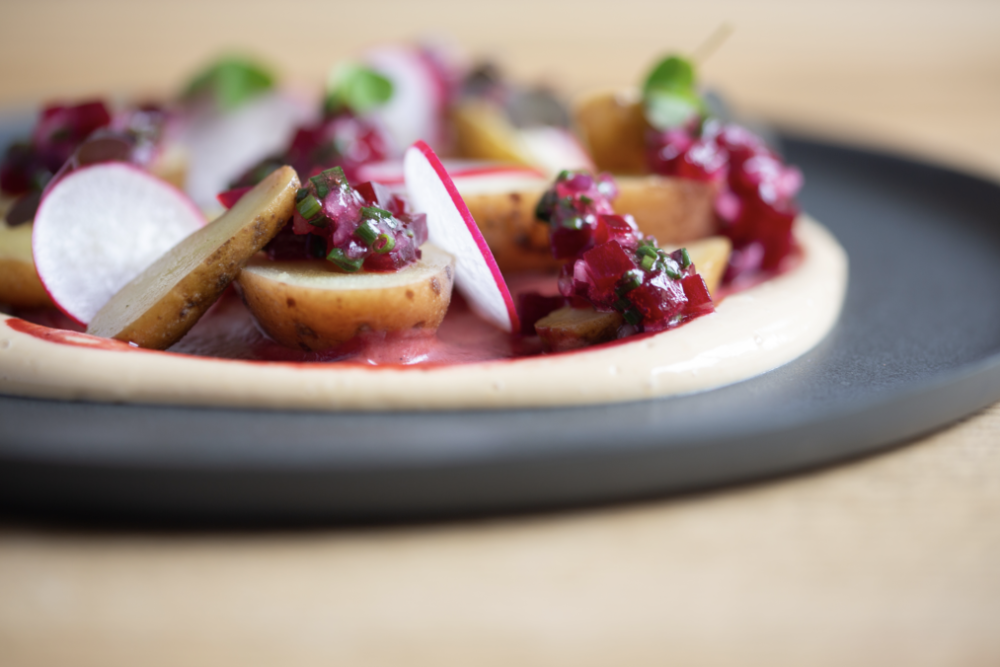 A beautifully plated gourmet dish with crisp radishes resting on silky potato purée, served on classic Swiss tableware.