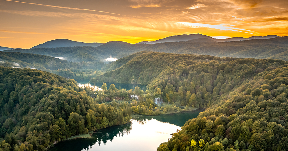 Sweeping sunset view of the forested valleys and turquoise, terraced lakes of Plitvice Lakes National Park in Croatia.