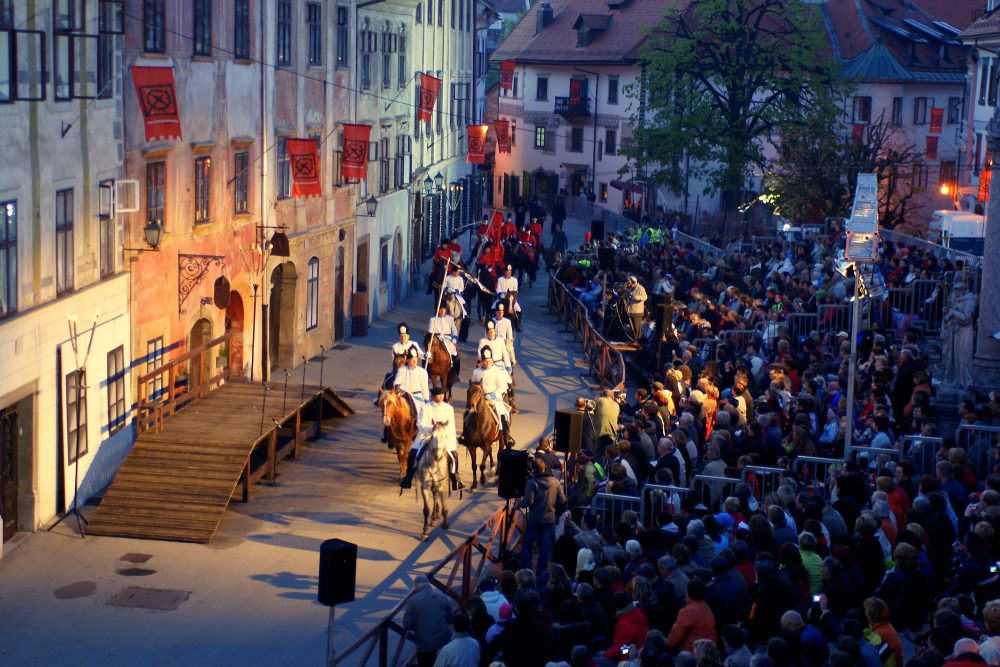 Open-air performance of the Škofja Loka Passion Play in Slovenia, with costumed actors on horseback and a large seated audience.