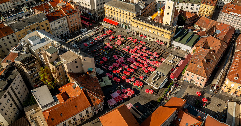 This image is an aerial view of Dolac Market, a well-known open-air farmers market in Zagreb, the capital of Croatia. It's located just above the main city square (Ban Jelačić Square) and is a vibrant hub for fresh produce, flowers, local goods, and traditional Croatian culture.