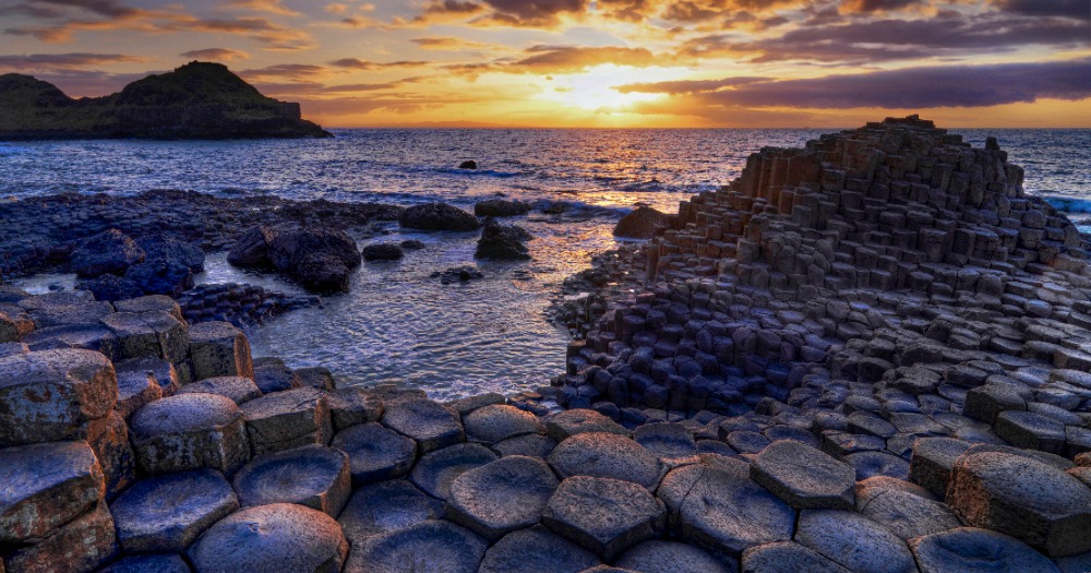 Sunset at a rocky coastline with hexagonal basalt colums and rocks.