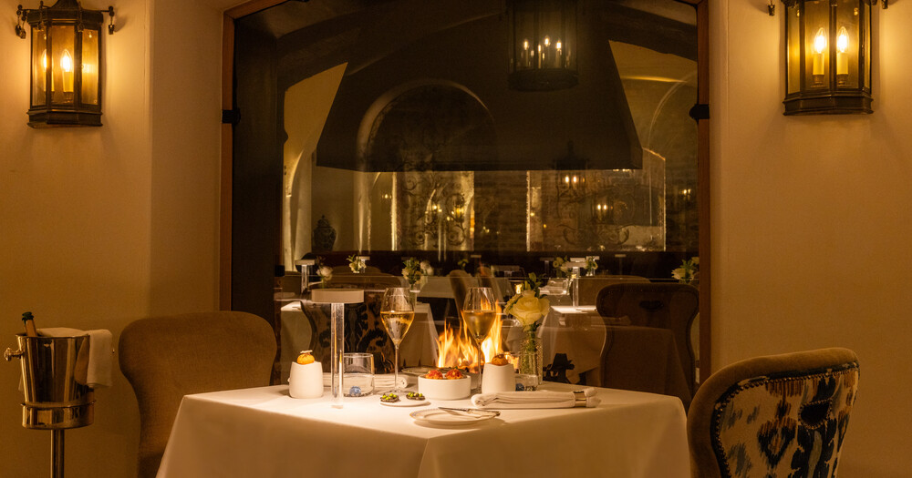 Elegant restaurant interior with set tables, candlelight, and wall lanterns.