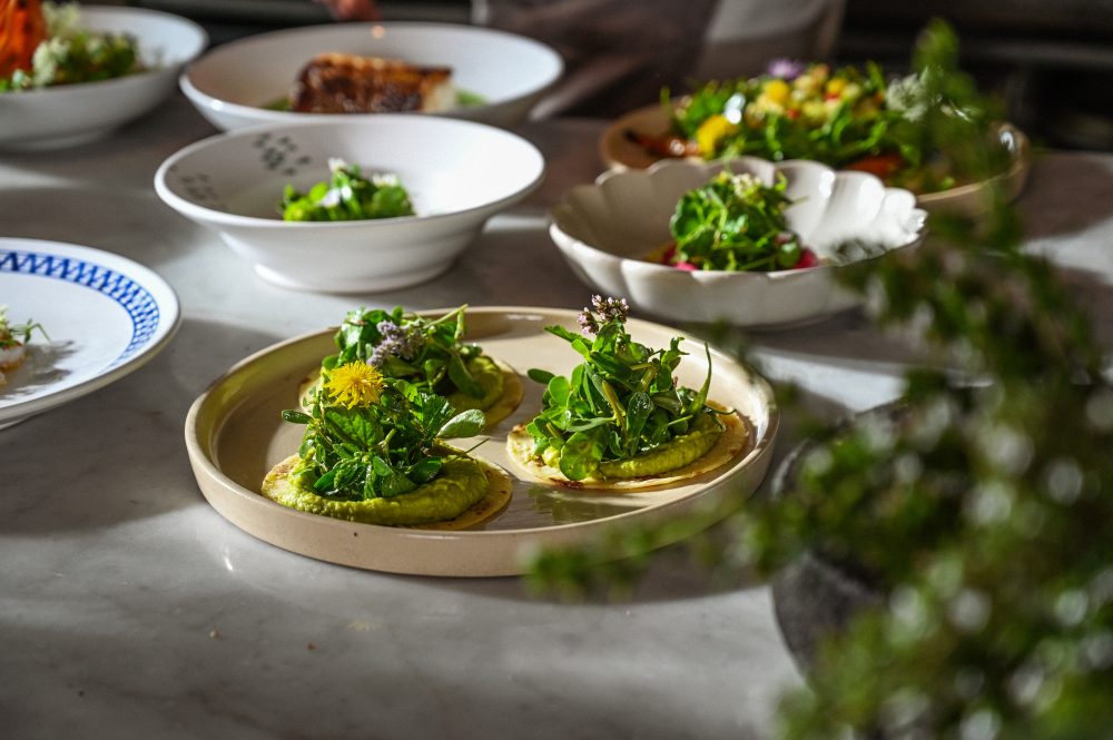 Close-up of a gourmet dish topped with fresh greens and edible flowers, served at a Slow Food-inspired dining event.