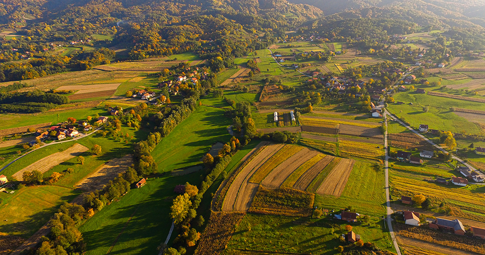 Aerial view of the rural Zagorje region in Croatia, showing patchwork green and yellow fields, rolling hills, and small villages.