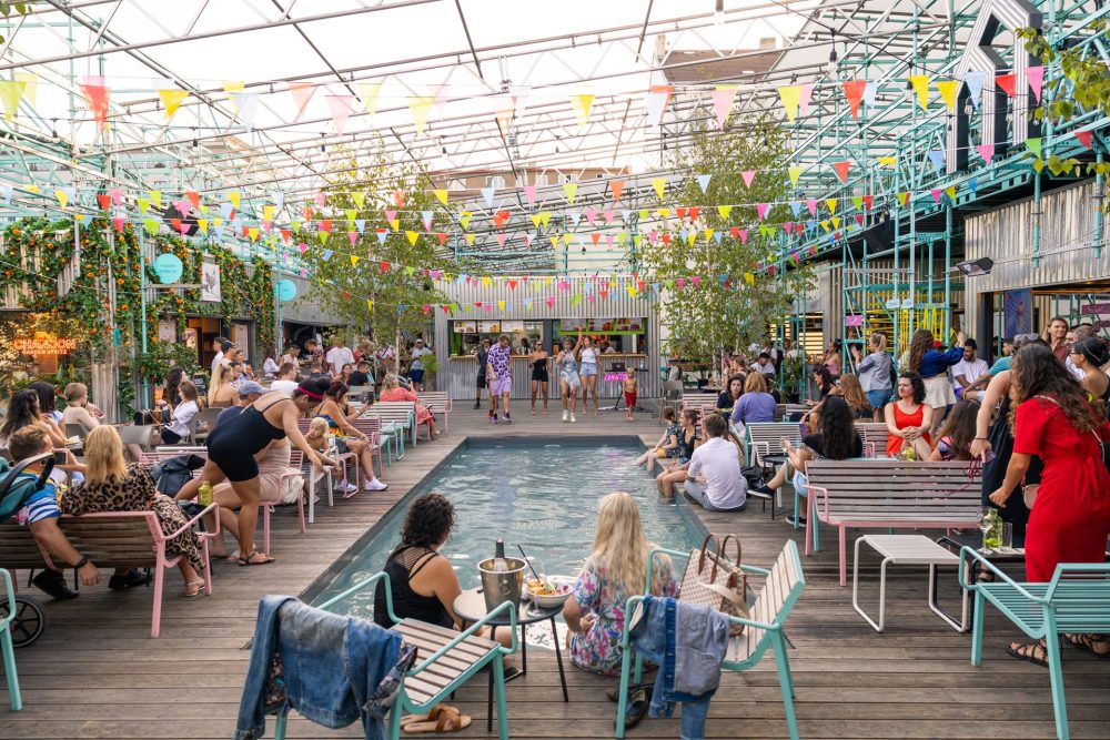 Bicycle and stalls along the riverside at Naplavka Farmers’ Market in Prague, with locals browsing fresh produce on a sunny day.