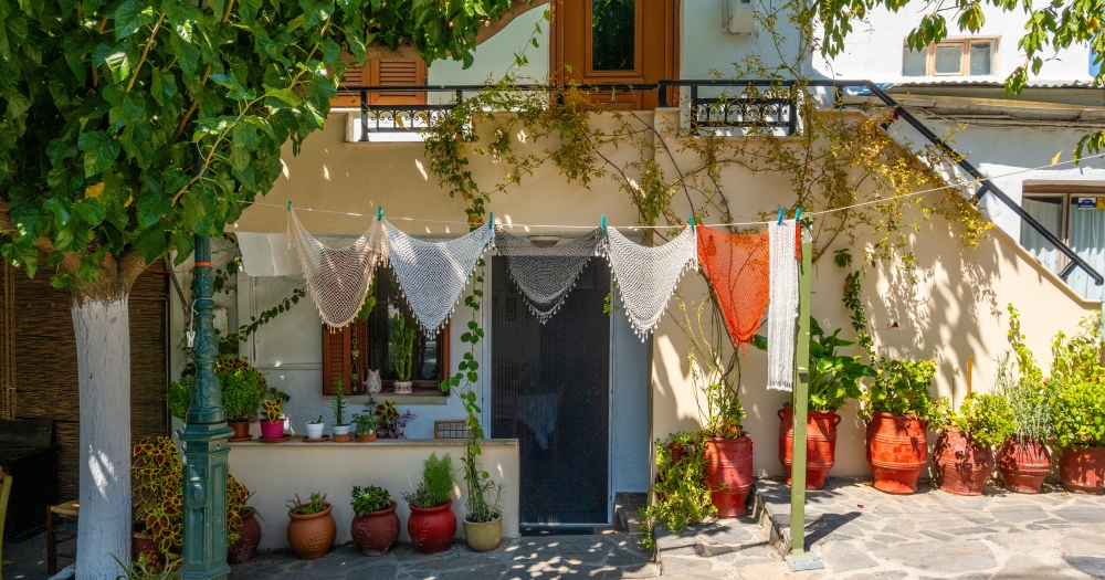 Quaint house front with hanging lace, plants in pots, and a green lamp post.